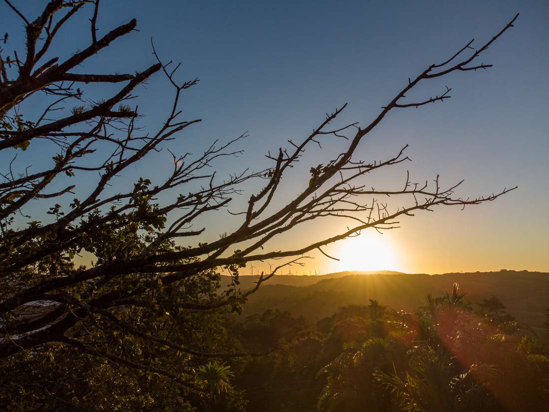 Sol ocultándose detrás de las montañas y las torres eólicas al atardecer